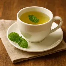 Grüner Tee mit Minze Green mint breeze Tasse weiß Leintuch Holztisch
